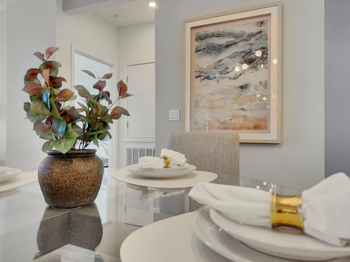 A beautifully set dining table in an elegant, welcoming environment, accented by decorative plants and wall art. The scene evokes intimate dinners and festive gatherings, reflecting warmth and style.