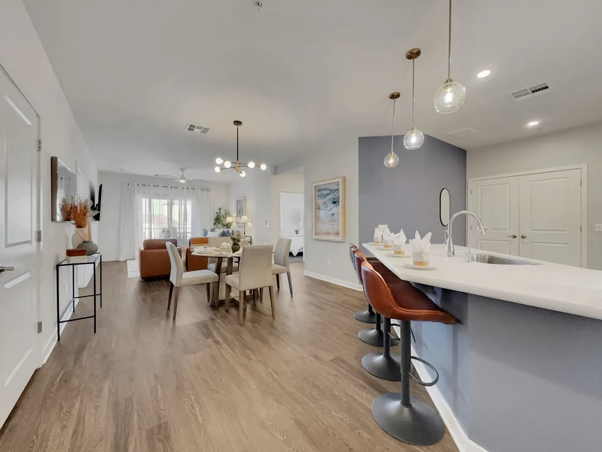 A stylish dining area with a dining table, bar stools, pendant lights, and wall artwork. The setting is inviting and designed for both cozy family dinners or gatherings with friends.