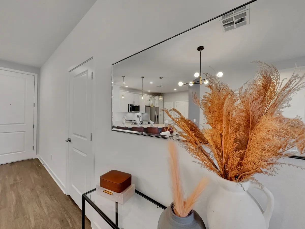 A welcoming entryway featuring a decorative vase with dried plants, a mirror, and an entryway table. The scene is inviting and showcases the first impression guests receive when entering the property.